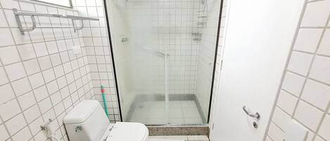 A small, tiled bathroom with a toilet, a shower stall, and a glass door.