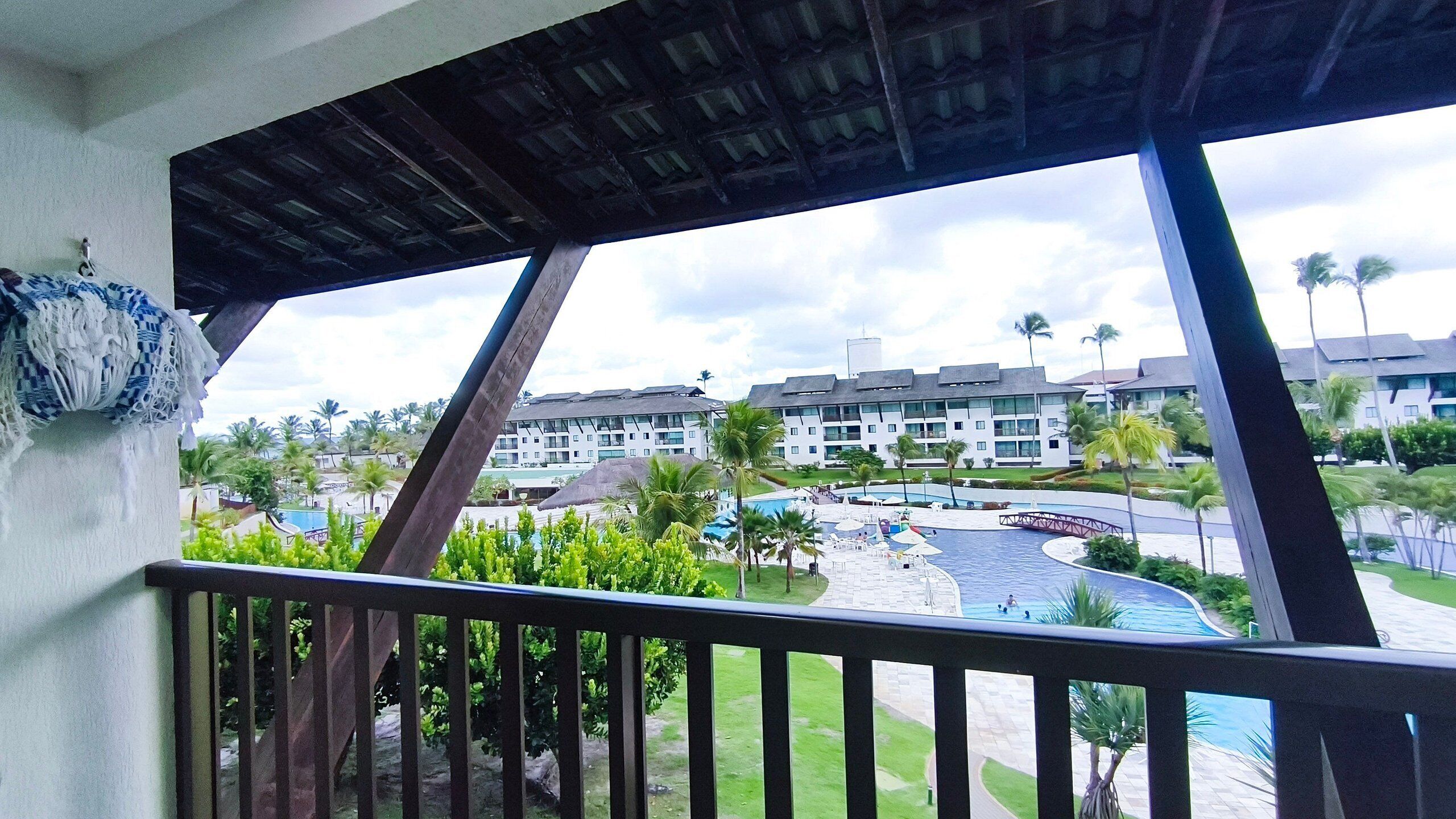 A hotel with a pool, palm trees, and a view of the surrounding area.