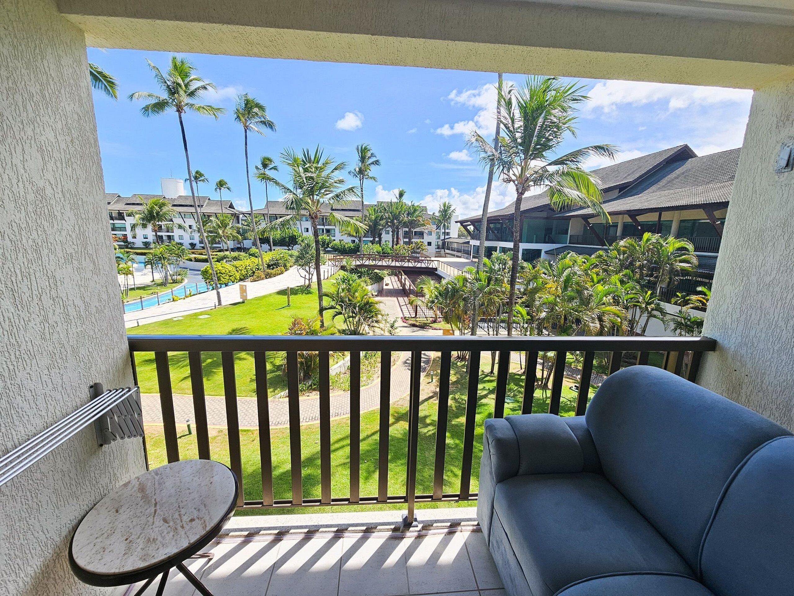 A balcony with a view of a resort area, including a pool and palm trees.