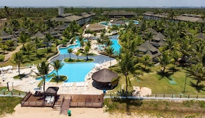 Um resort com várias piscinas, palmeiras e edifícios do resort.