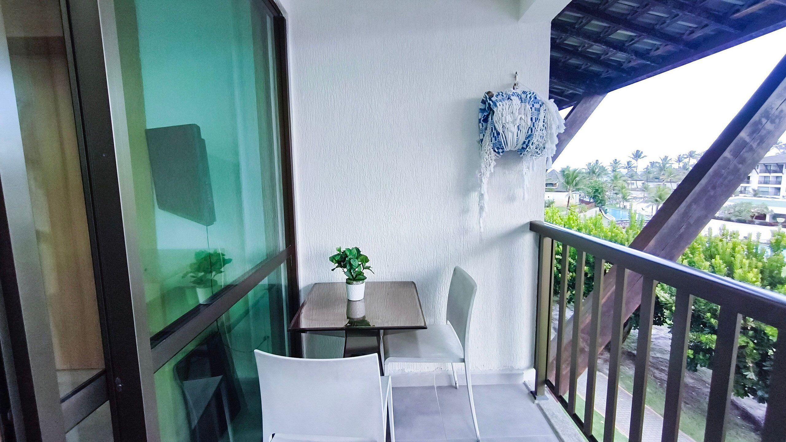 A balcony with a table and chairs, a potted plant, and a view of the surrounding area.