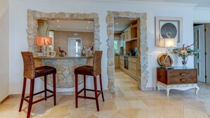 A kitchen with stone archways, two bar stools, a wooden cabinet, and a decorative vase. - Bay D Townhouse With Roof Top Jacuzzi and Sea Views (Carvoeiro)
