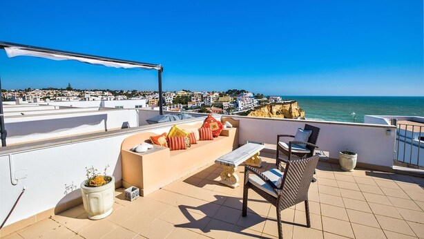 A rooftop terrace with a seating area, a table, and a view of the sea and town. - Bay D Townhouse With Roof Top Jacuzzi and Sea Views (Carvoeiro)