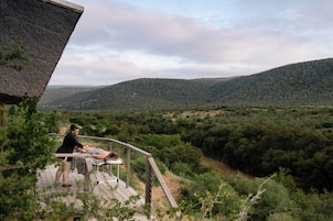 Una terraza de madera con una persona recibiendo un masaje, con vistas a un valle y colinas boscosas.