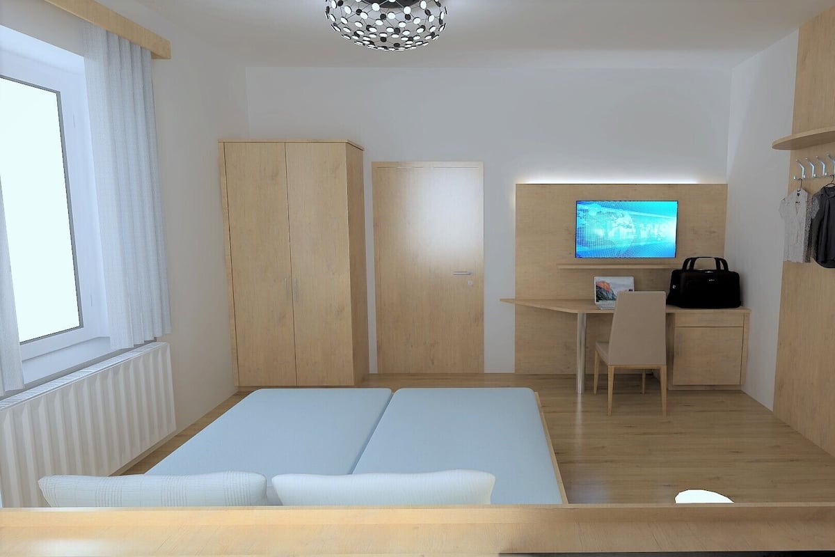 Ein modernes Schlafzimmer mit Bett, Schreibtisch und Fernseher.