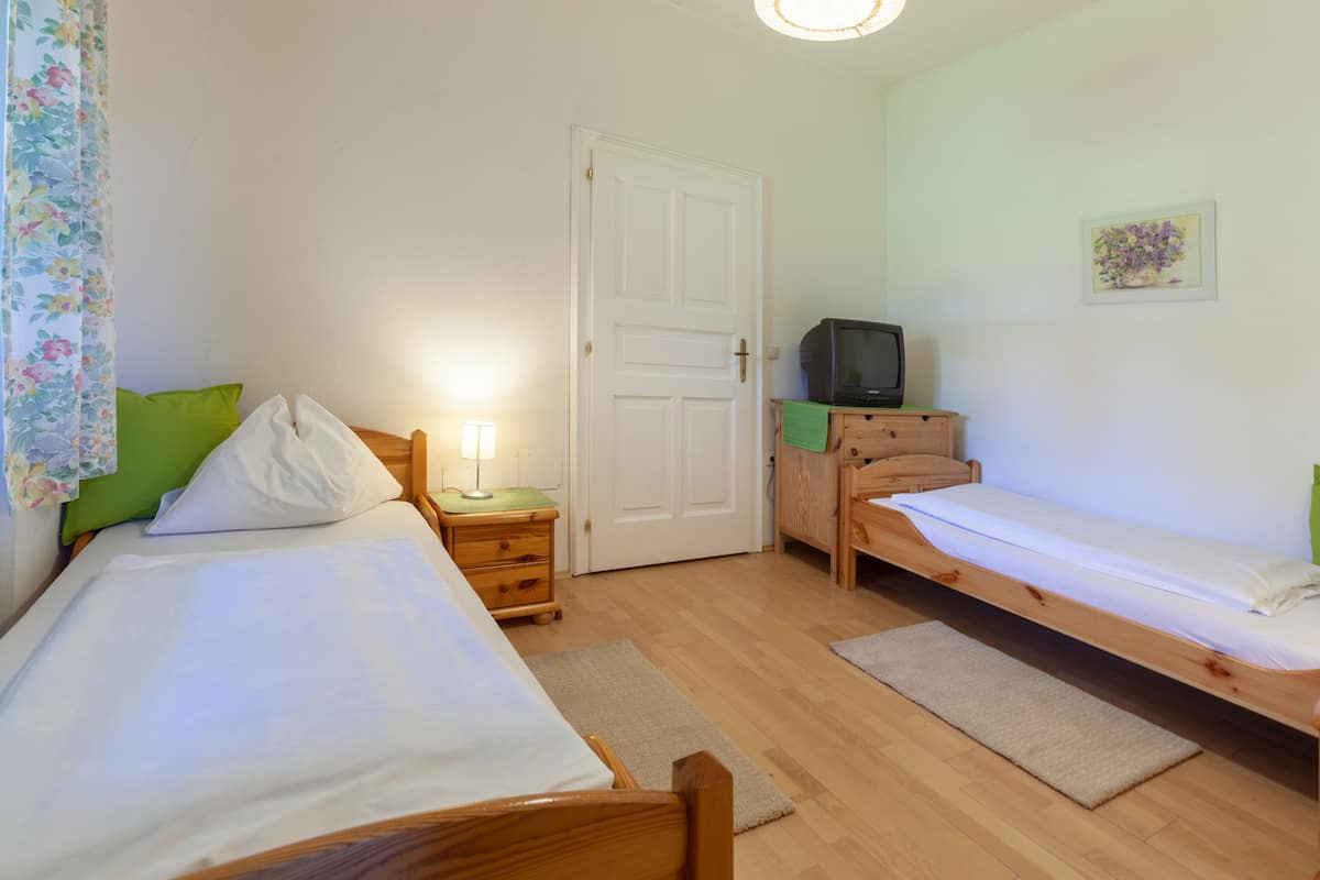 Ein Zimmer mit zwei Betten, einem Fernseher auf einer Holzkommode und einer Tür.