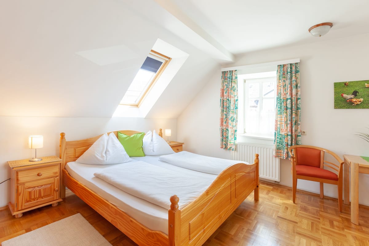 Ein Schlafzimmer mit einem hölzernen Bett, einem Nachttisch, einem Schreibtisch und einem Stuhl.