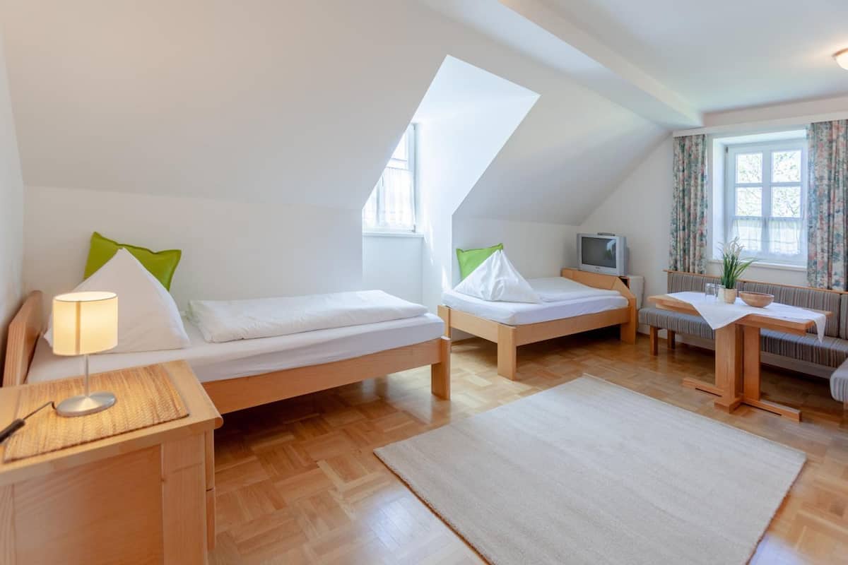 Ein gemütliches Schlafzimmer im Dachgeschoss mit zwei Einzelbetten, einem kleinen Schreibtisch und einem Fernseher.