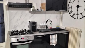 A modern kitchen with a gas stove, oven, and microwave, a black countertop, and a clock on the wall. - rental in the heart of Provence with private pool secured (Grans)