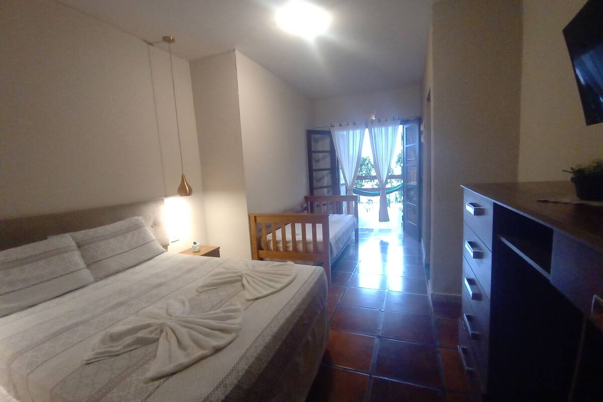 A bedroom with a bed, bedside table, and a view of a balcony.