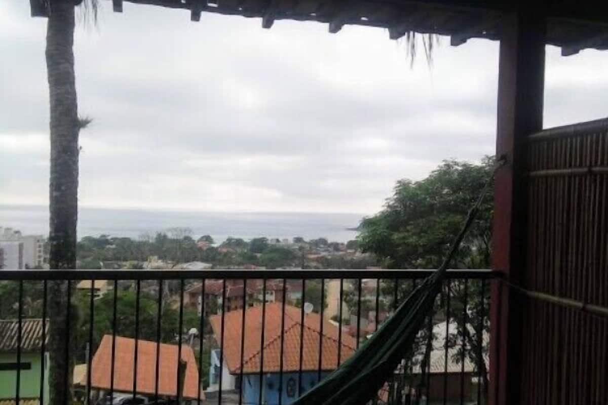 A hammock on a wooden deck with a view of a residential area and a body of water in the background.