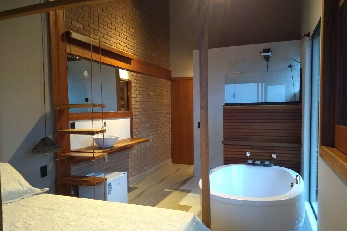 A modern bathroom with a large bathtub, a wooden vanity, and a hanging shelf with a bowl.