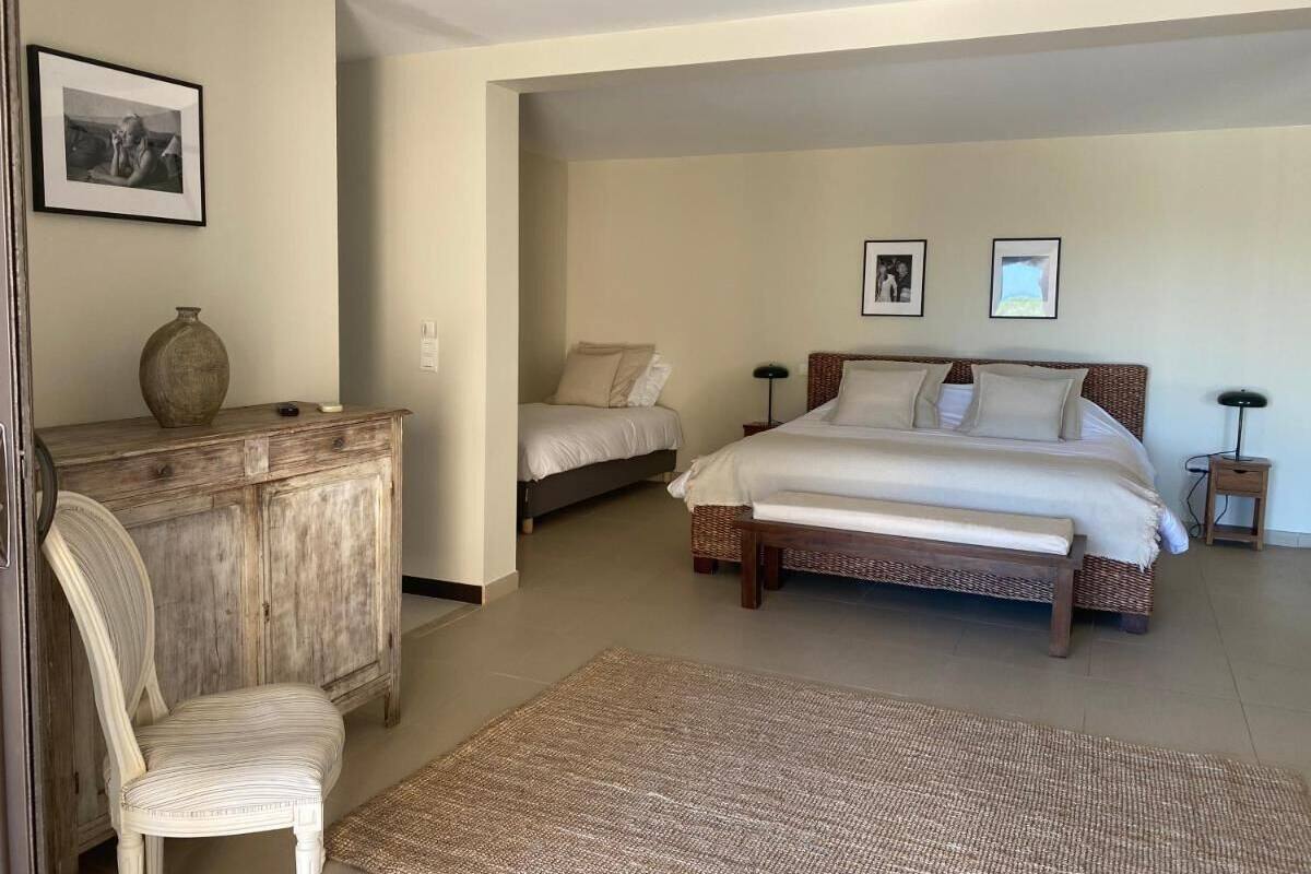 Une chambre avec un grand lit, un lit plus petit, une commode en bois et une chaise.