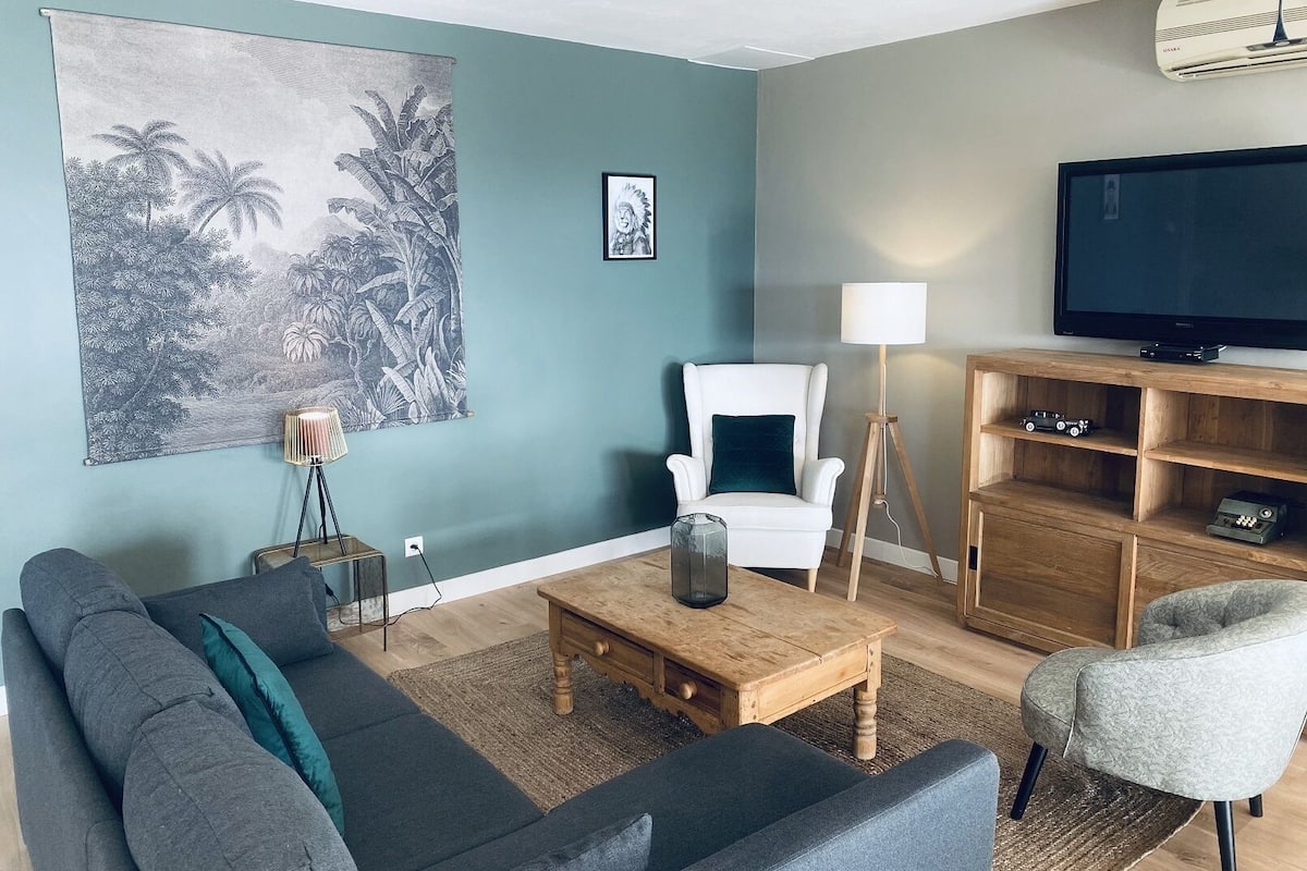 Un salon avec un canapé, une table basse, une lampe, un téléviseur et un tableau au mur.