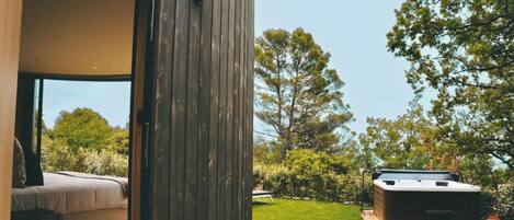 Un área moderna de hidromasaje al aire libre con una terraza de madera, rodeada de abundante vegetación y árboles.