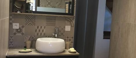 A bathroom with a large mirror, a sink, and a towel rack.