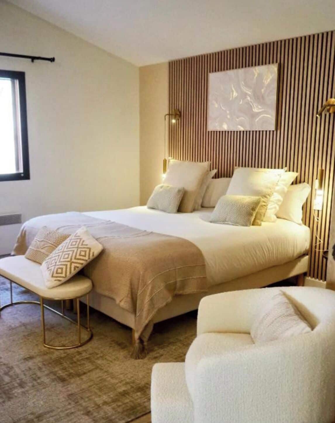 A modern hotel room with a large bed, two bedside tables, a bench, and a chair.