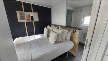 Une chambre à coucher moderne avec un lit, une tête de lit en bois, une étagère intégrée et un miroir au mur.