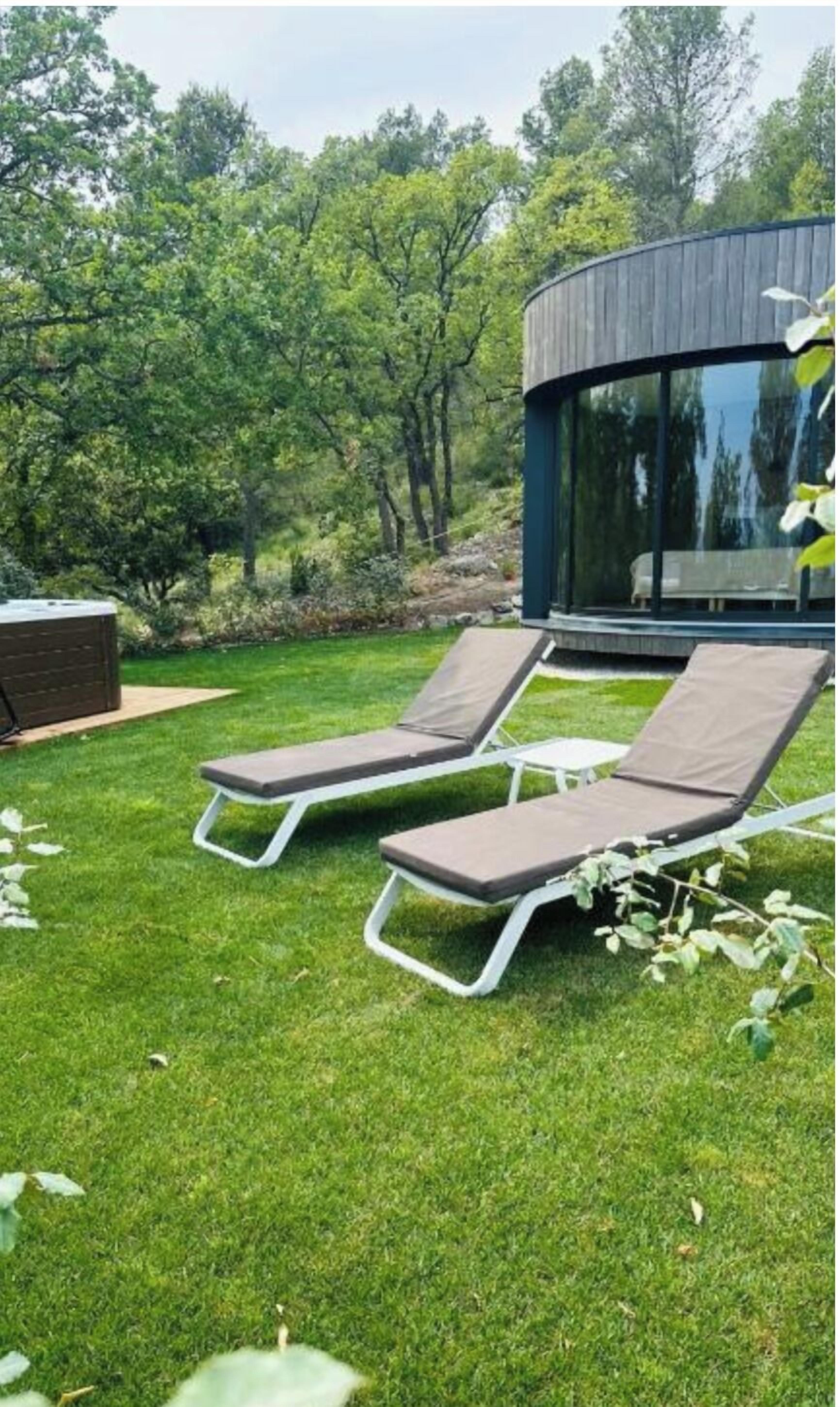 Zona d'estar a l'aire lliure i de disseny modern, amb dues gandules i una barbacoa integrada.