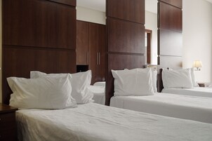 Una habitación de hotel con dos camas, armarios de madera y una mesita de noche con lámpara.