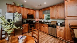 A kitchen with wooden cabinets, stainless steel appliances, and a dining area with a table and chairs.