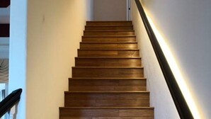 Een houten trap met een zwarte leuning en een lichtstrook langs de muur.