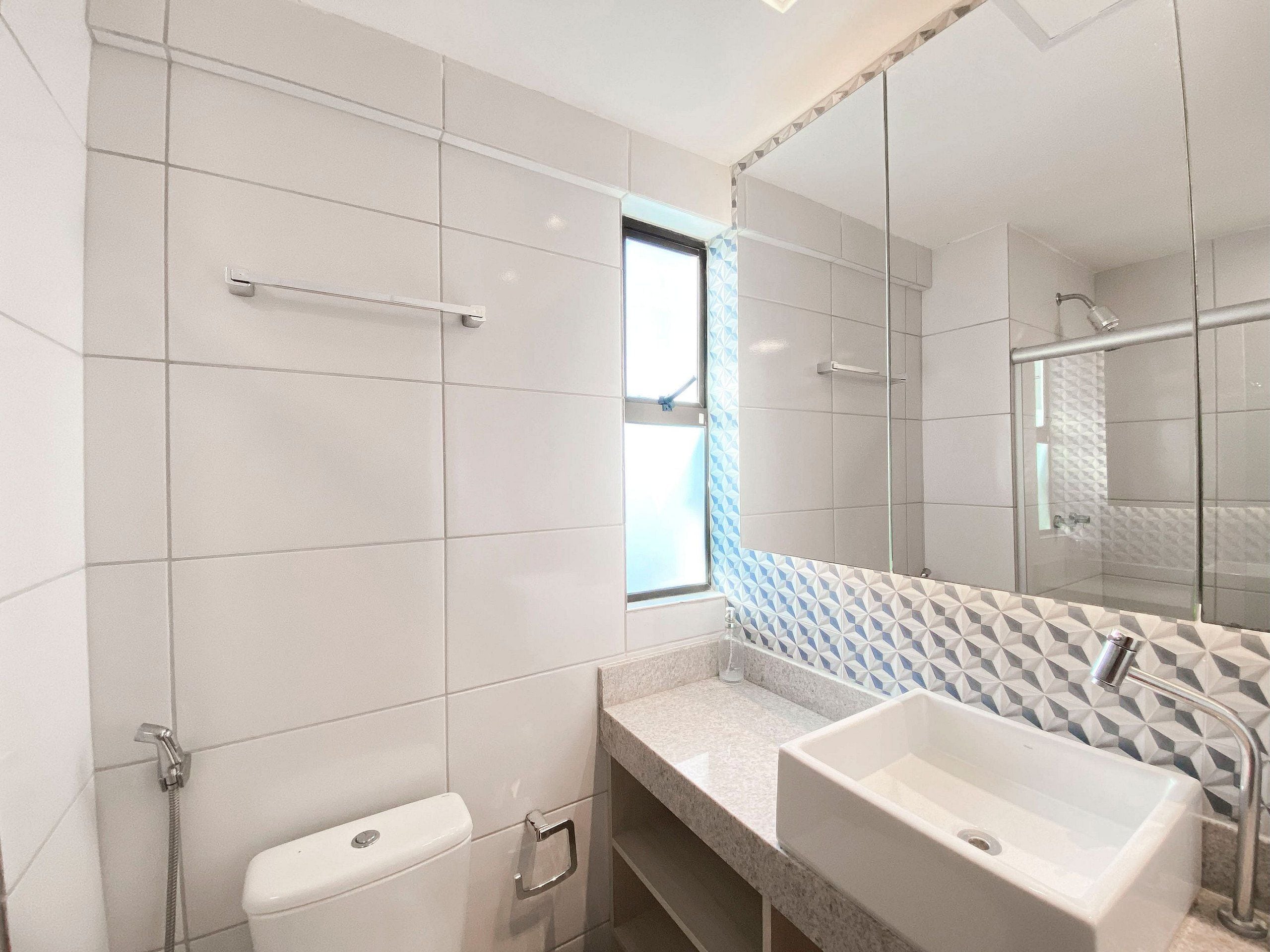 A modern bathroom with a large mirror, a shower enclosure, and a sink.