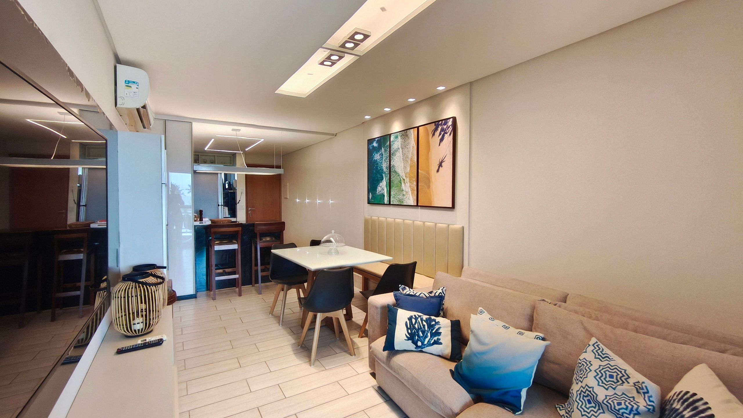 A modern living room with a sofa, a dining table, and a kitchen area.
