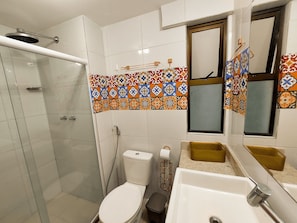 Une salle de bain équipée d’une douche, de toilettes, d’un lavabo et d’un miroir.