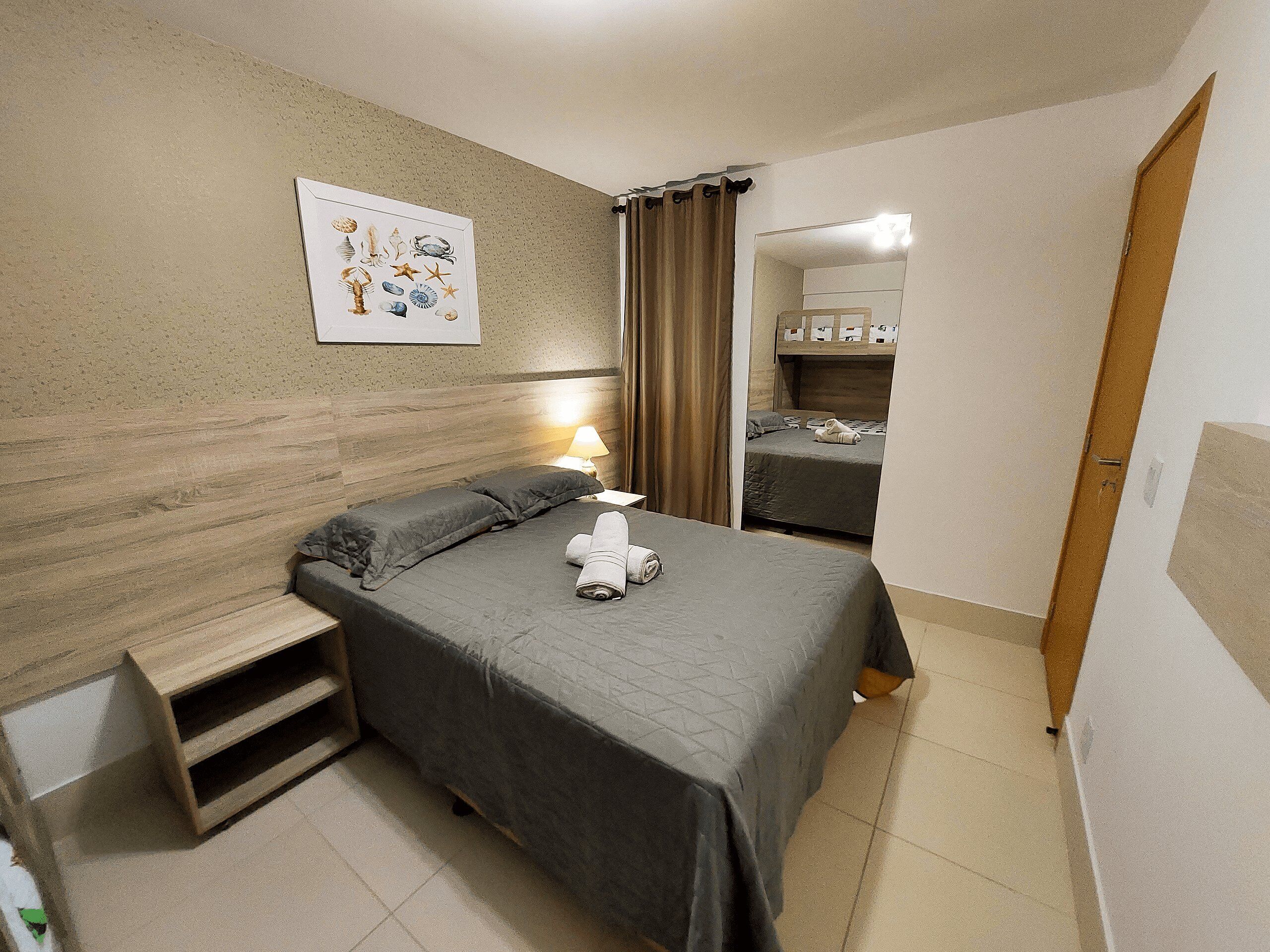 Une chambre à coucher avec un lit, une table de chevet, une lampe, un tableau accroché au mur et une porte en bois.