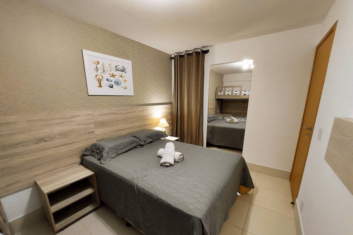 Un dormitorio con cama, mesita de noche, lámpara, un cuadro en la pared y una puerta de madera.
