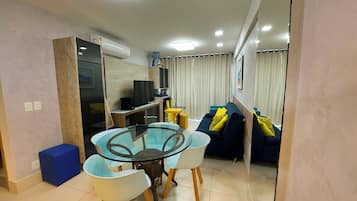 Un espacio habitable compacto con una mesa de comedor, sillas, un sofá, un televisor y una pequeña cocina.