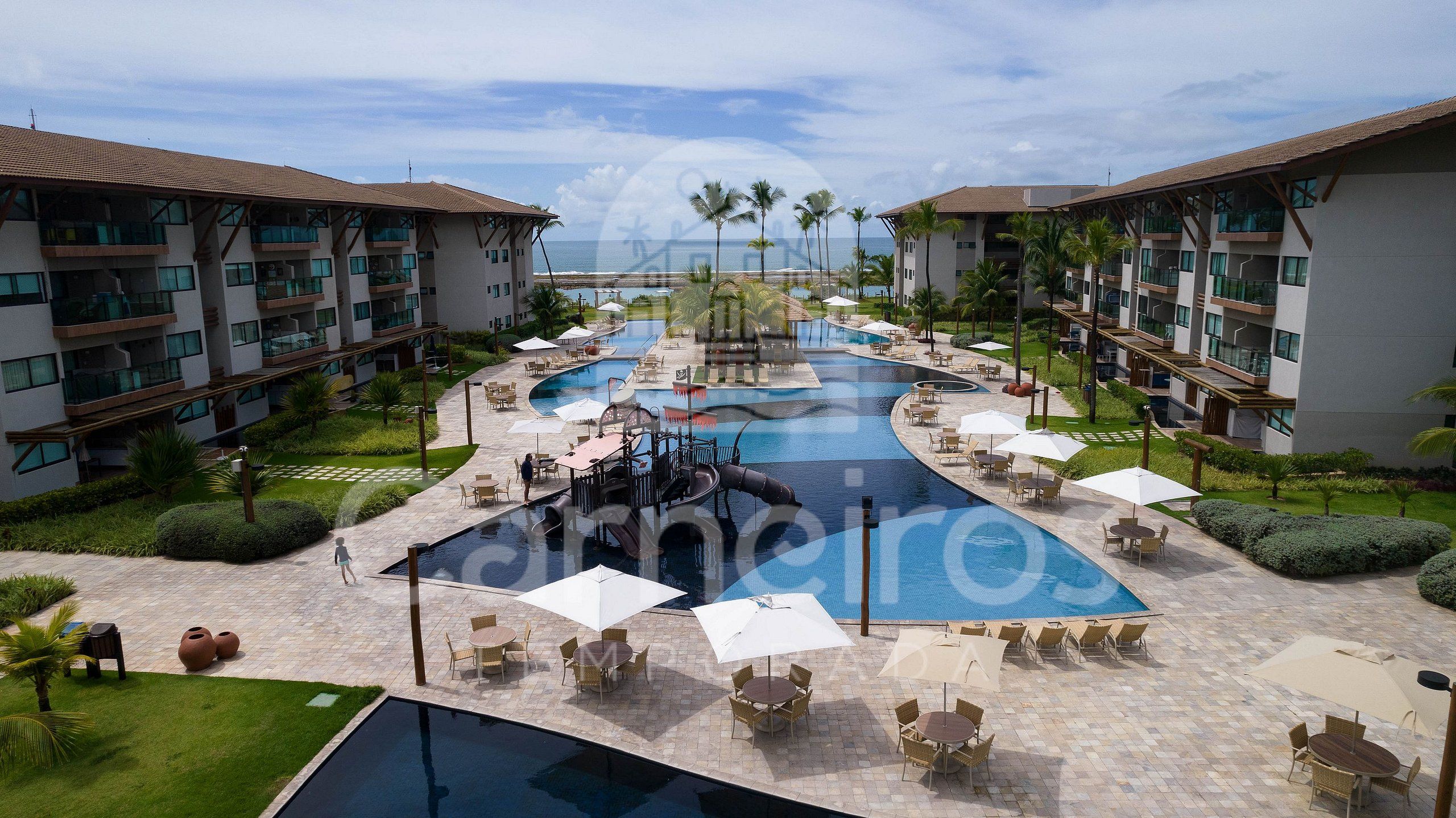 Een resort met een centraal gelegen zwembad, terras en moderne gebouwen.