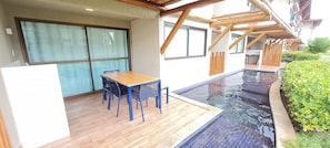 A poolside area with a wooden deck, a table with chairs, and a glass-enclosed room. - Flats no La Fleur Polinésia Residence (Ipojuca)