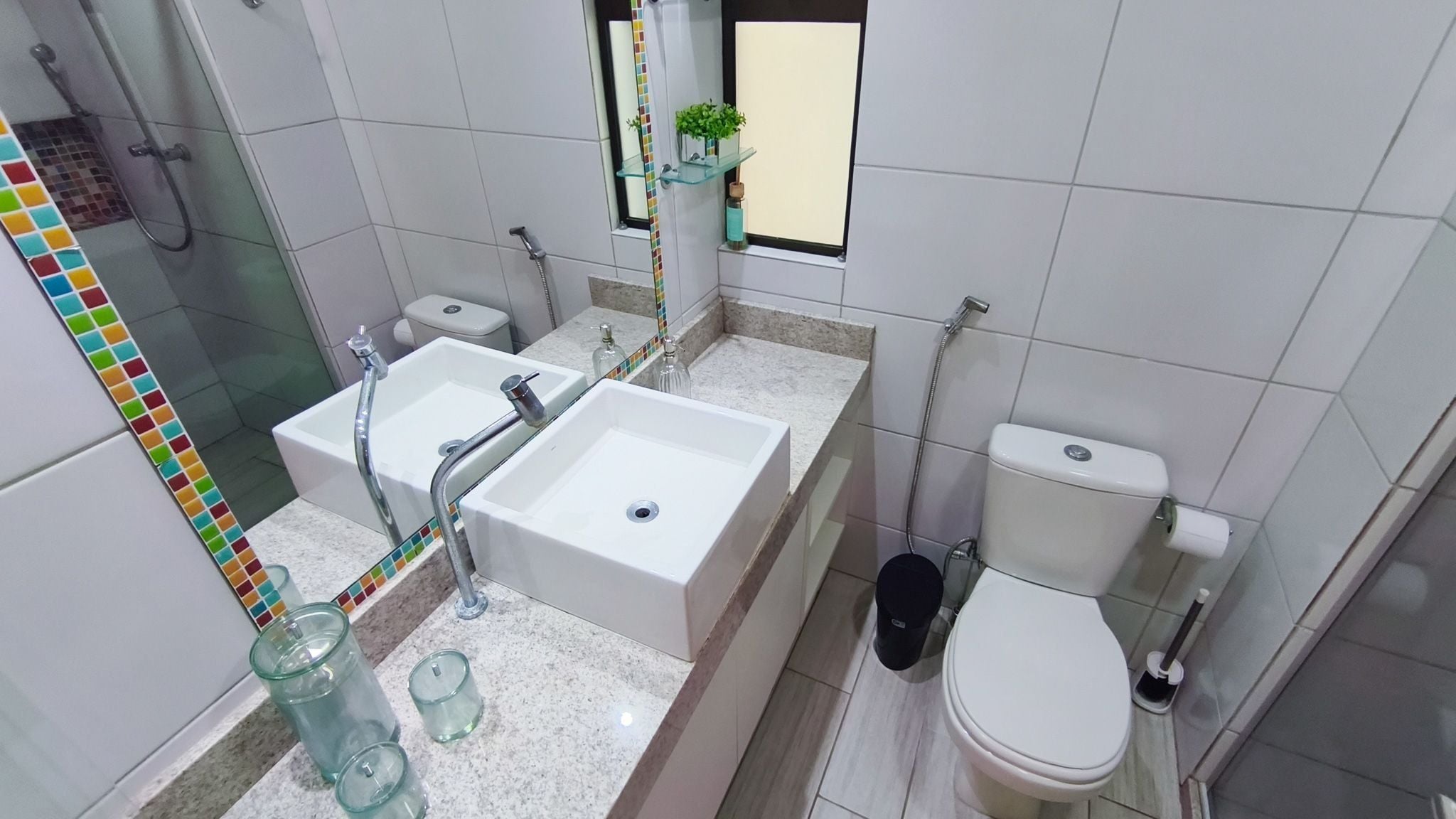 A bathroom with a double sink, a toilet, and a shower.