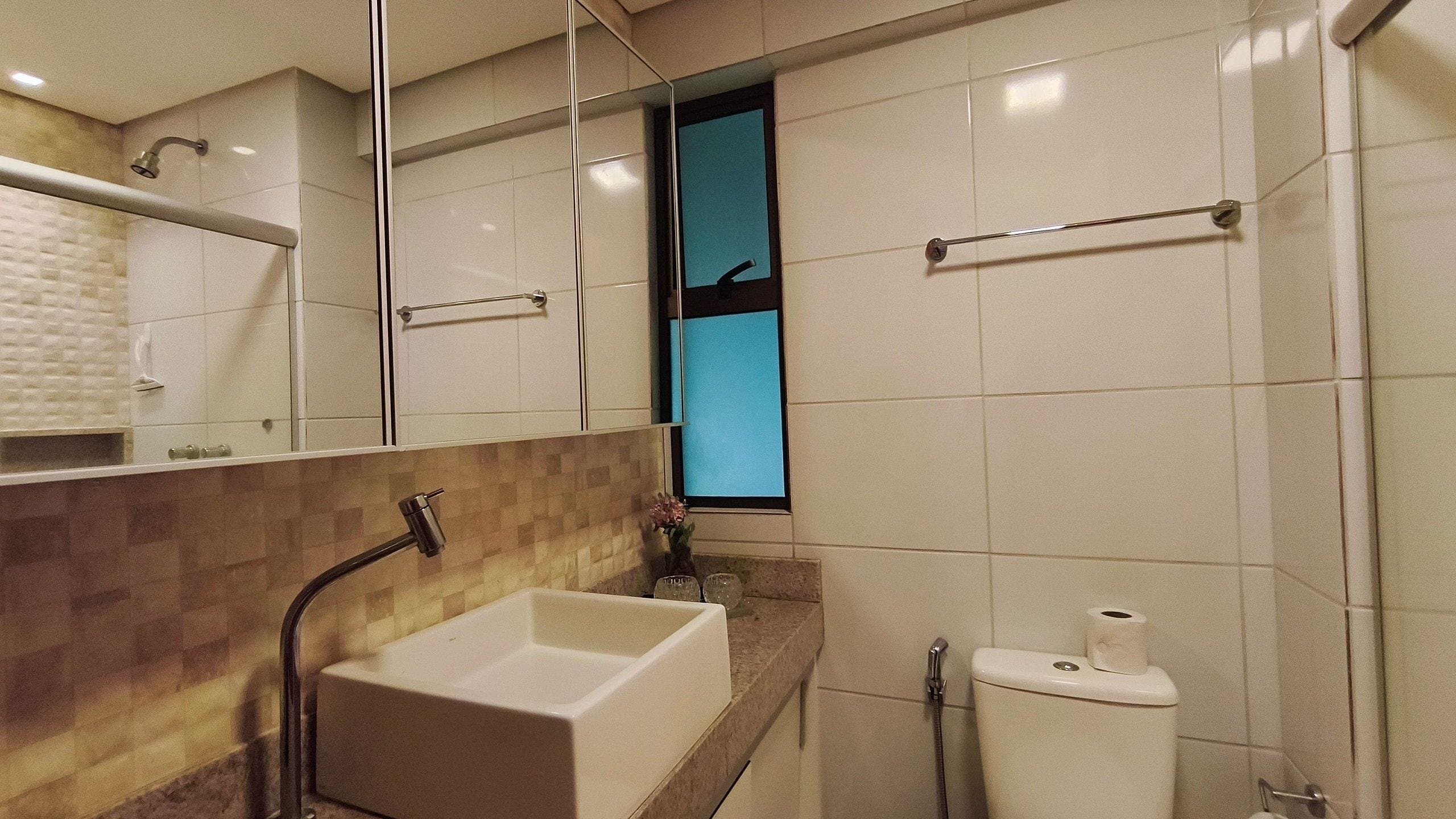 Un baño con lavamanos blanco, un espejo, inodoro y zona de ducha.