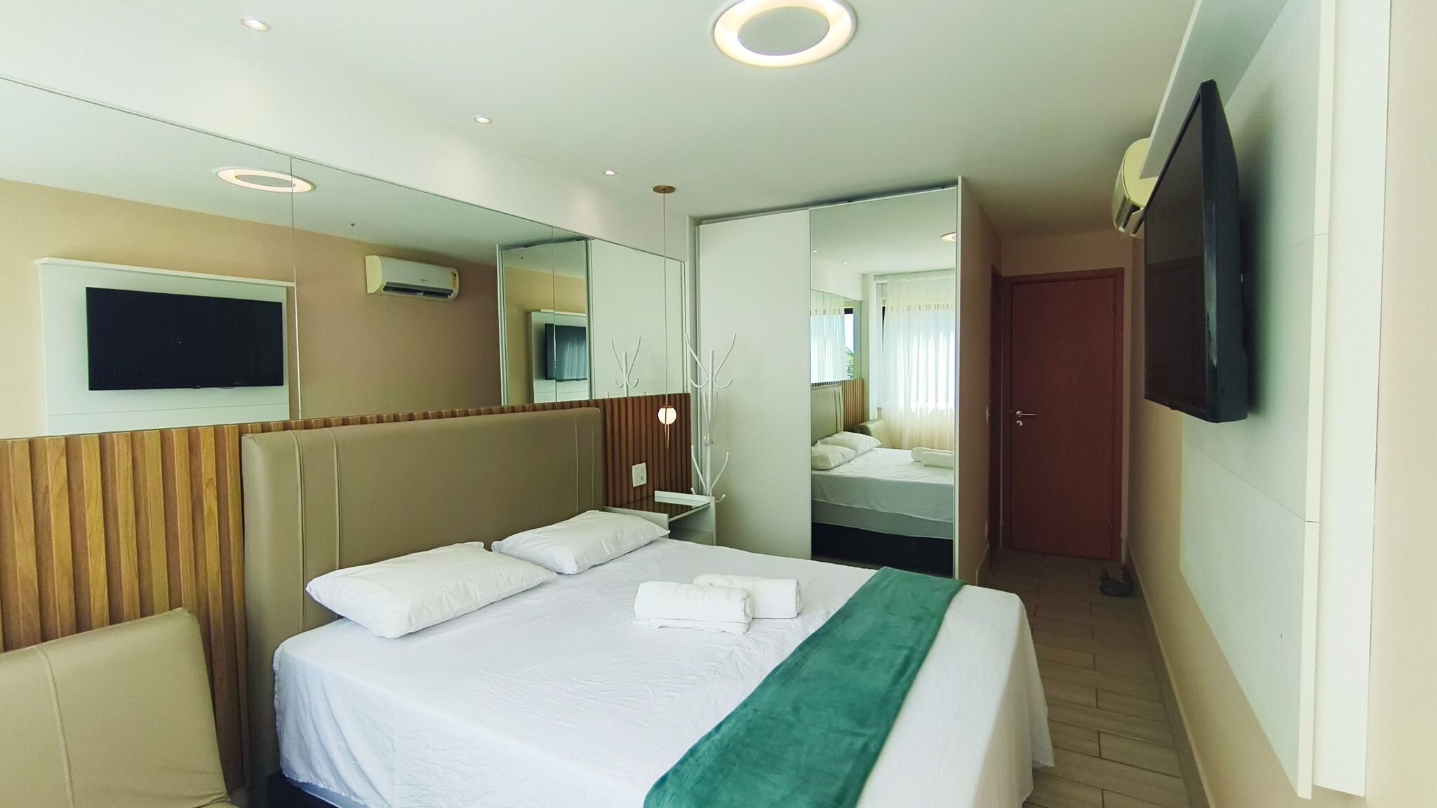 Une chambre d’hôtel équipée d’un lit, d’une télévision, d’un miroir et d’une porte donnant accès à une salle de bain.