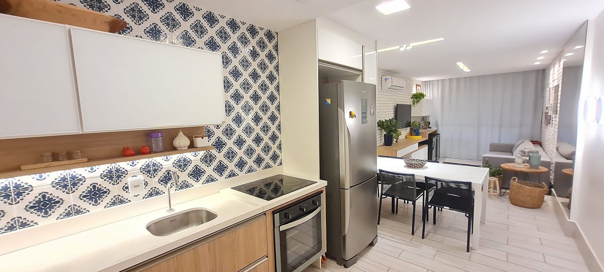 A modern kitchen with a built-in stove, refrigerator, and dining area with chairs.