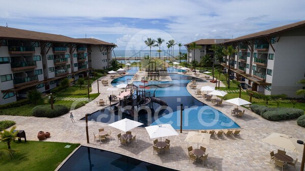 A resort with a central swimming pool, outdoor seating, and modern buildings.