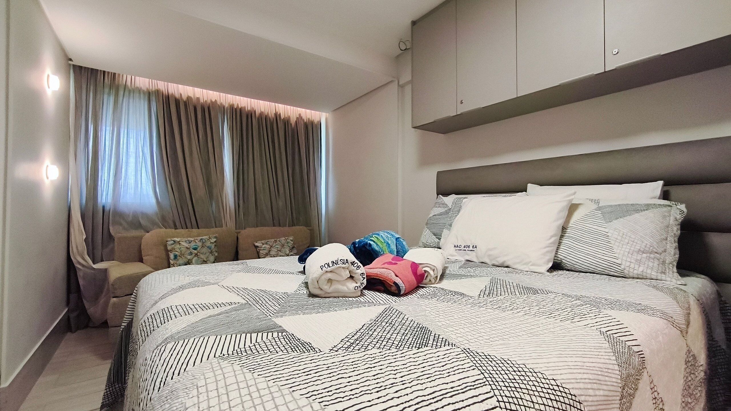 Une chambre d’hôtel avec un lit, un canapé, une fenêtre avec des rideaux et une tête de lit.