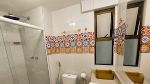 Un baño con ducha, inodoro, lavamanos y espejo.