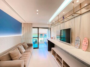 Een moderne woonkamer met een bank, televisie en surfplanken aan de muur.
