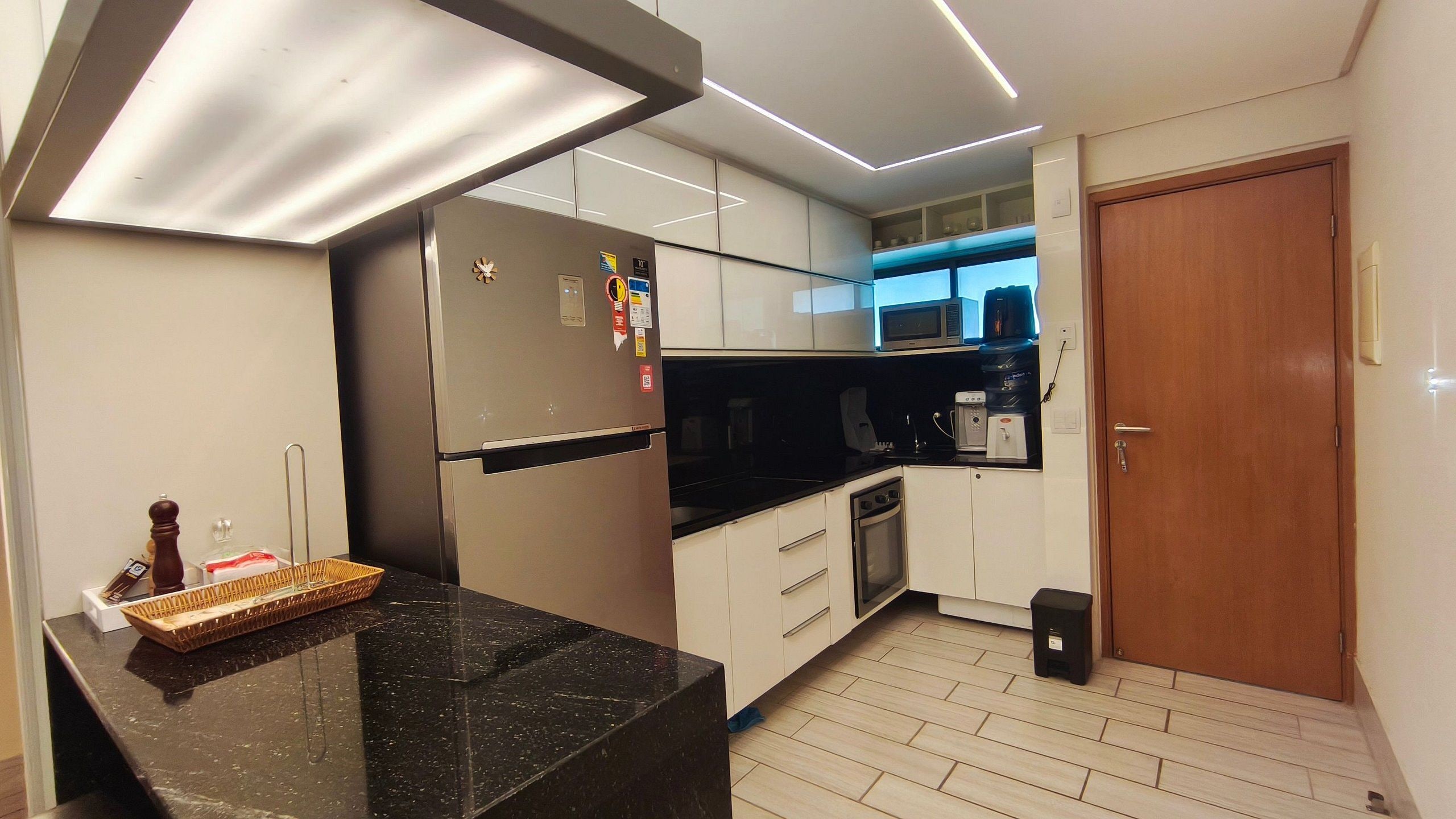A modern kitchen with a refrigerator, microwave, coffee machine, and a small sink.