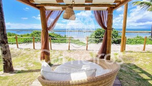 A beachside gazebo with a wicker chair and cushions, overlooking the sea. - Flats no La Fleur Polinésia Residence (Ipojuca)