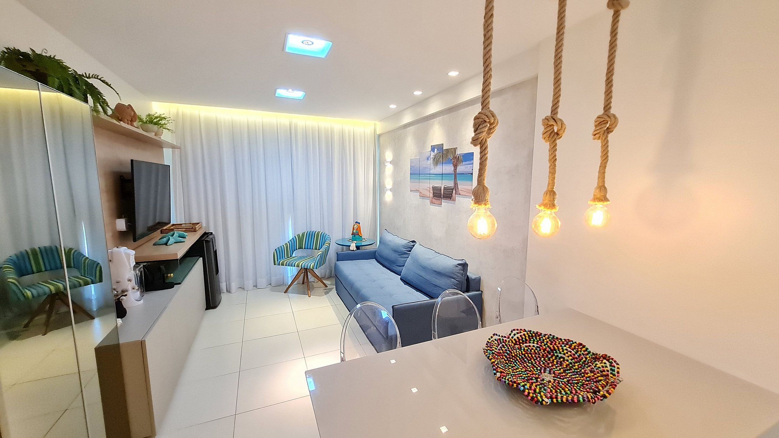 A modern living room with a sofa, a coffee table, a TV, and a dining area with a table and chairs.