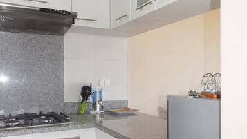 Quarto casal família, 2 quartos, 2 banheiros, vista parcial para o mar | Cozinha privada | Geladeira grande, micro-ondas, fogão, cooktop