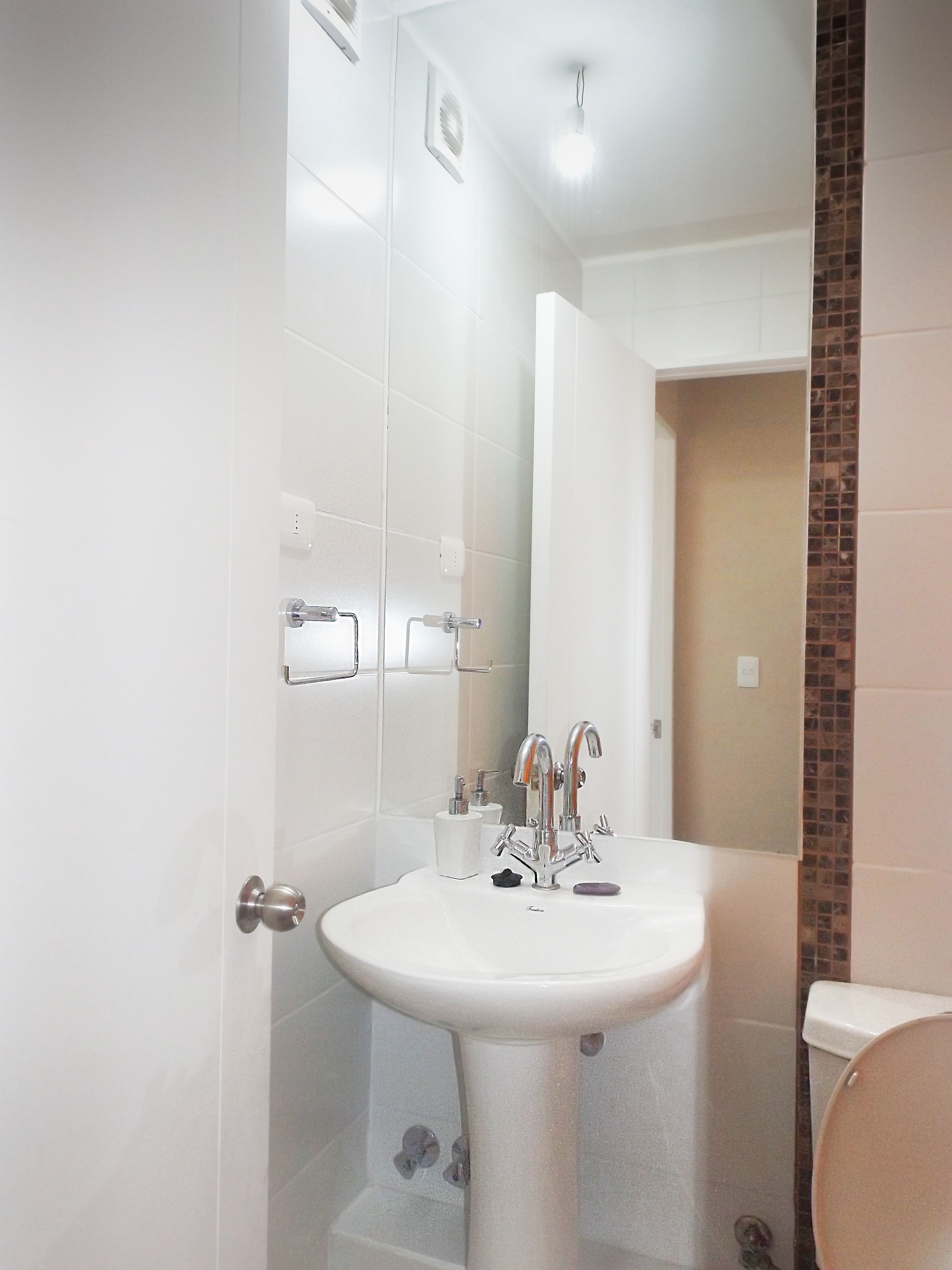 A bathroom with a white sink, a mirror, and a toilet.