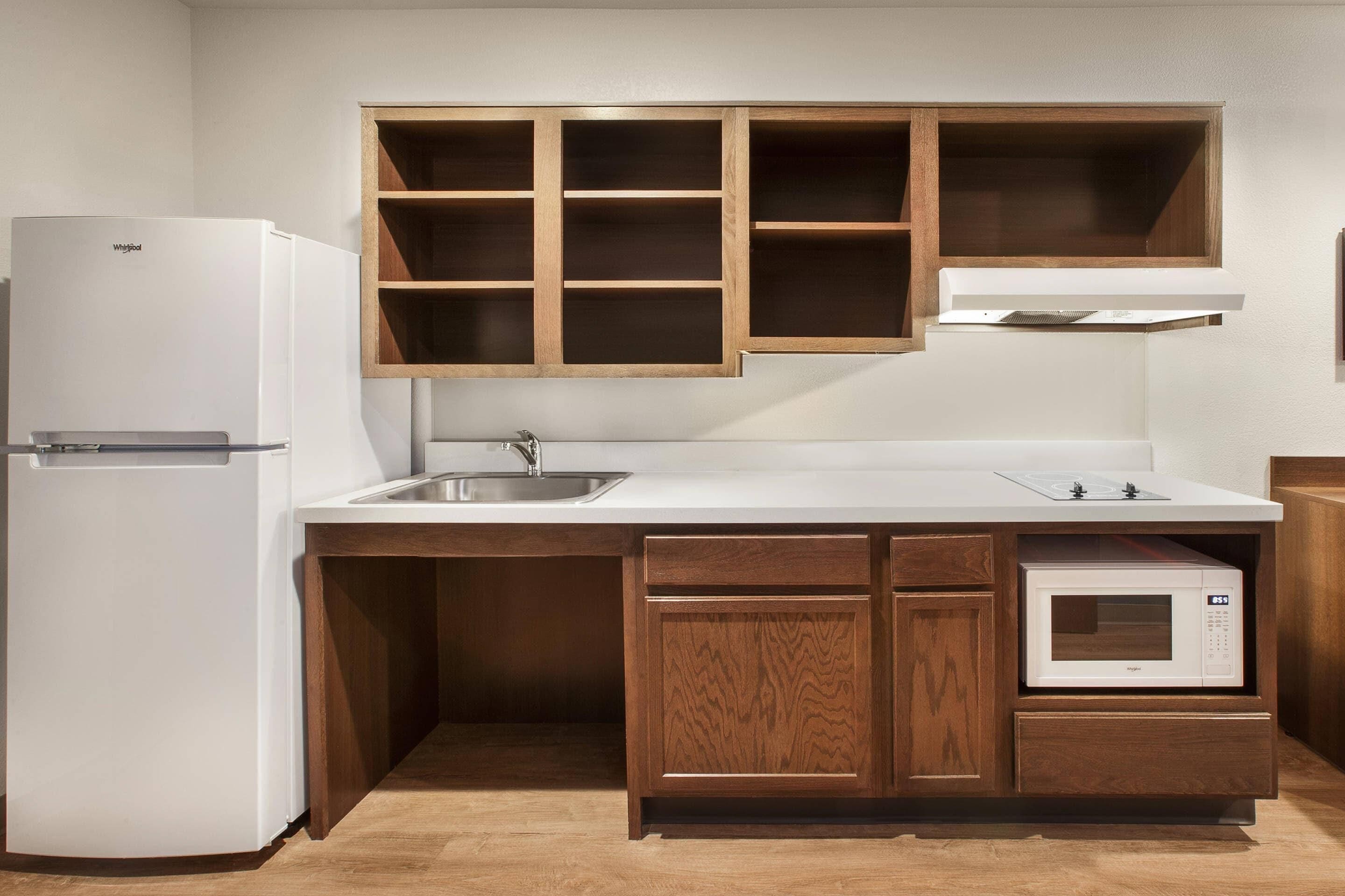 A compact kitchen with a built-in refrigerator, a microwave, and wooden cabinets.