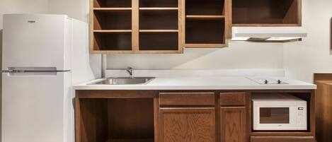 A compact kitchen with a built-in refrigerator, a microwave, and wooden cabinets.
