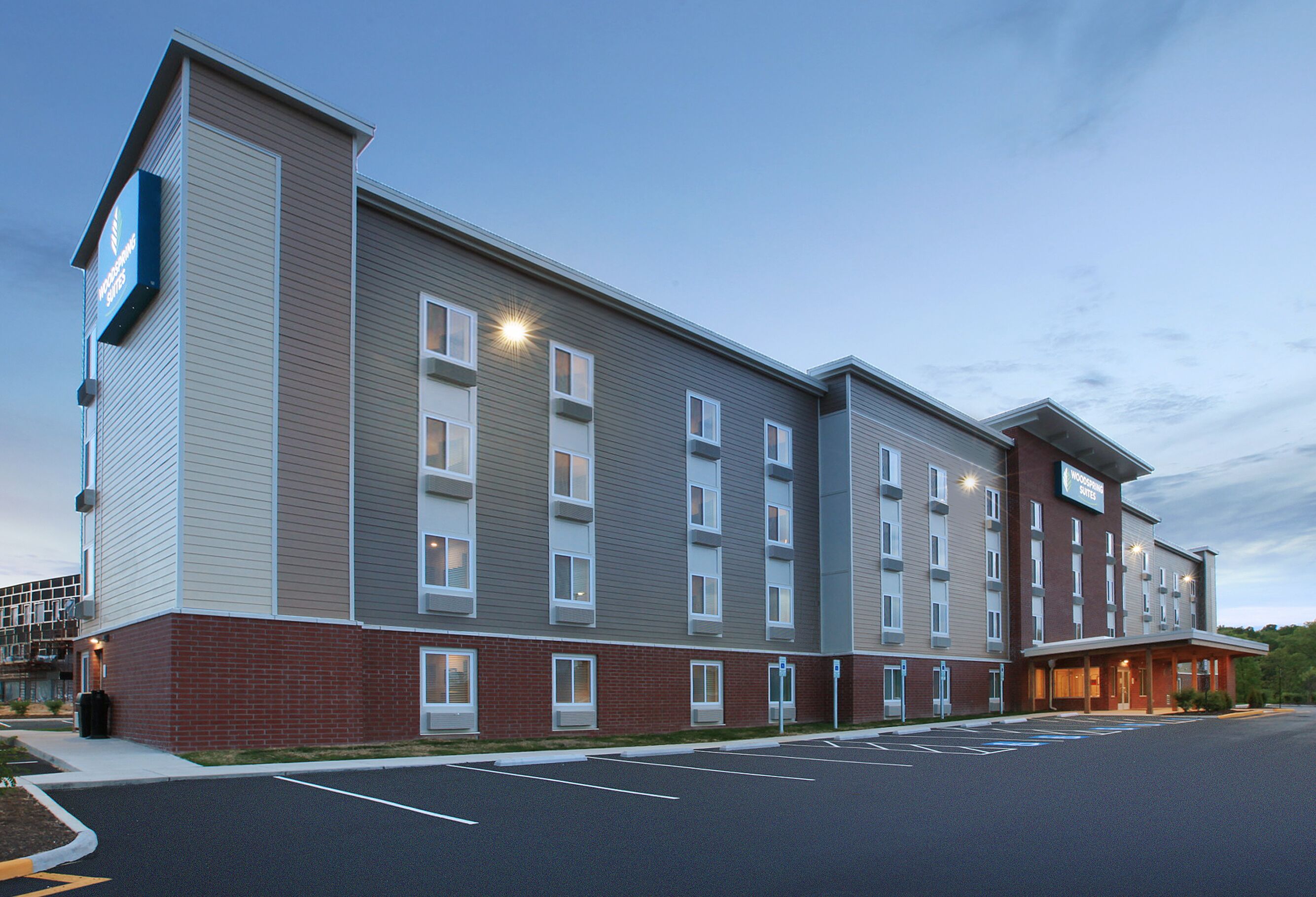 A multi-story hotel with a brick facade, multiple windows, and a parking lot.